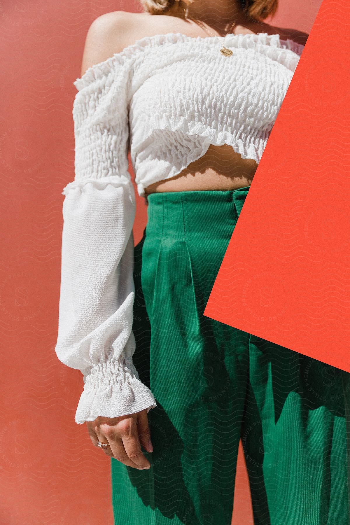 A woman holds an orange posterboard as she models a summer outfit