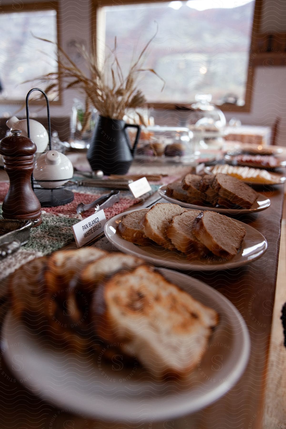 Table setting with assorted slices of bread laid out on a breakfast table with other foods out of focus