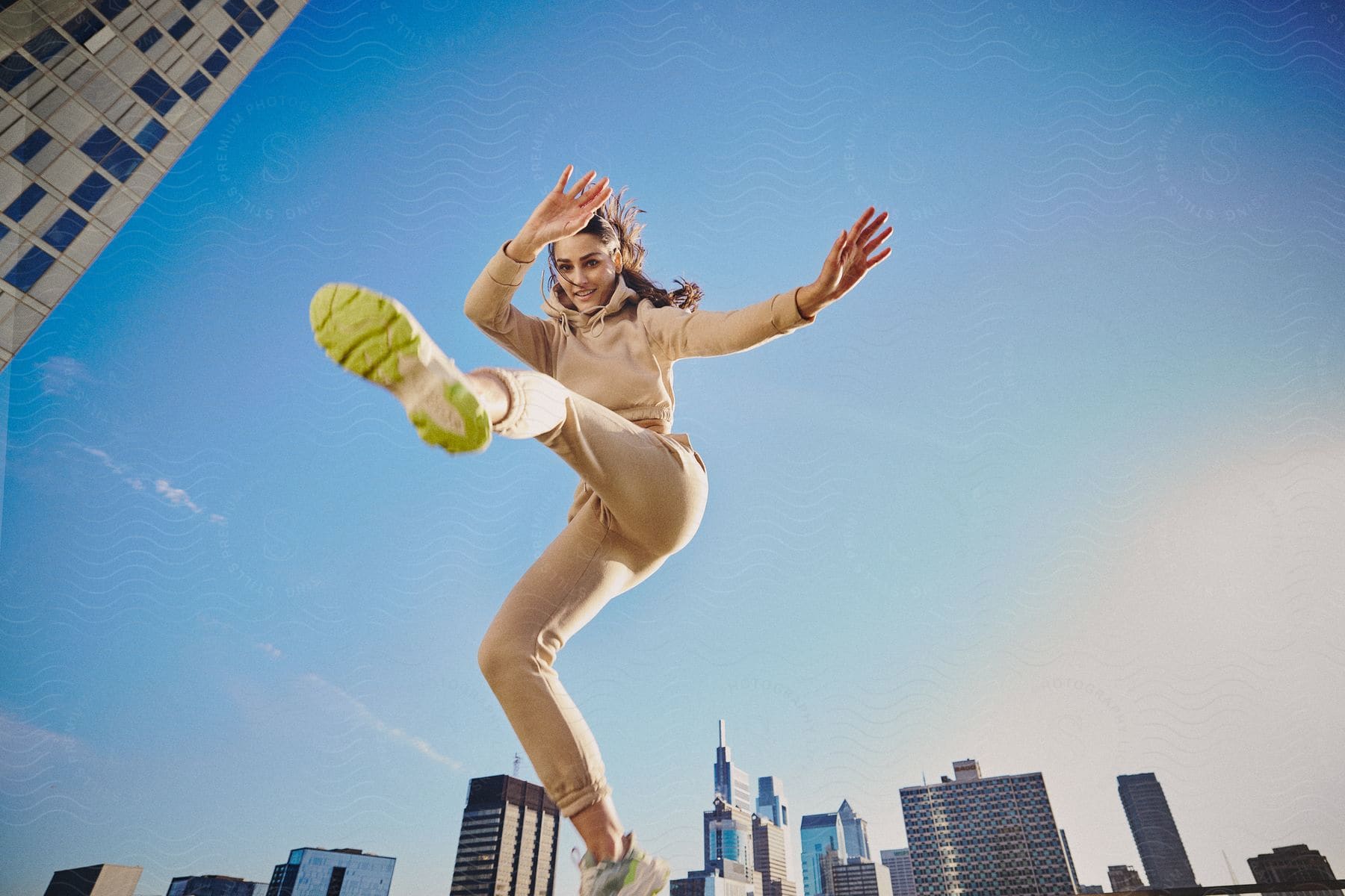 Stock photo of woman with yellow soled shoes jumps into the air with downtown skyscrapers in the background.