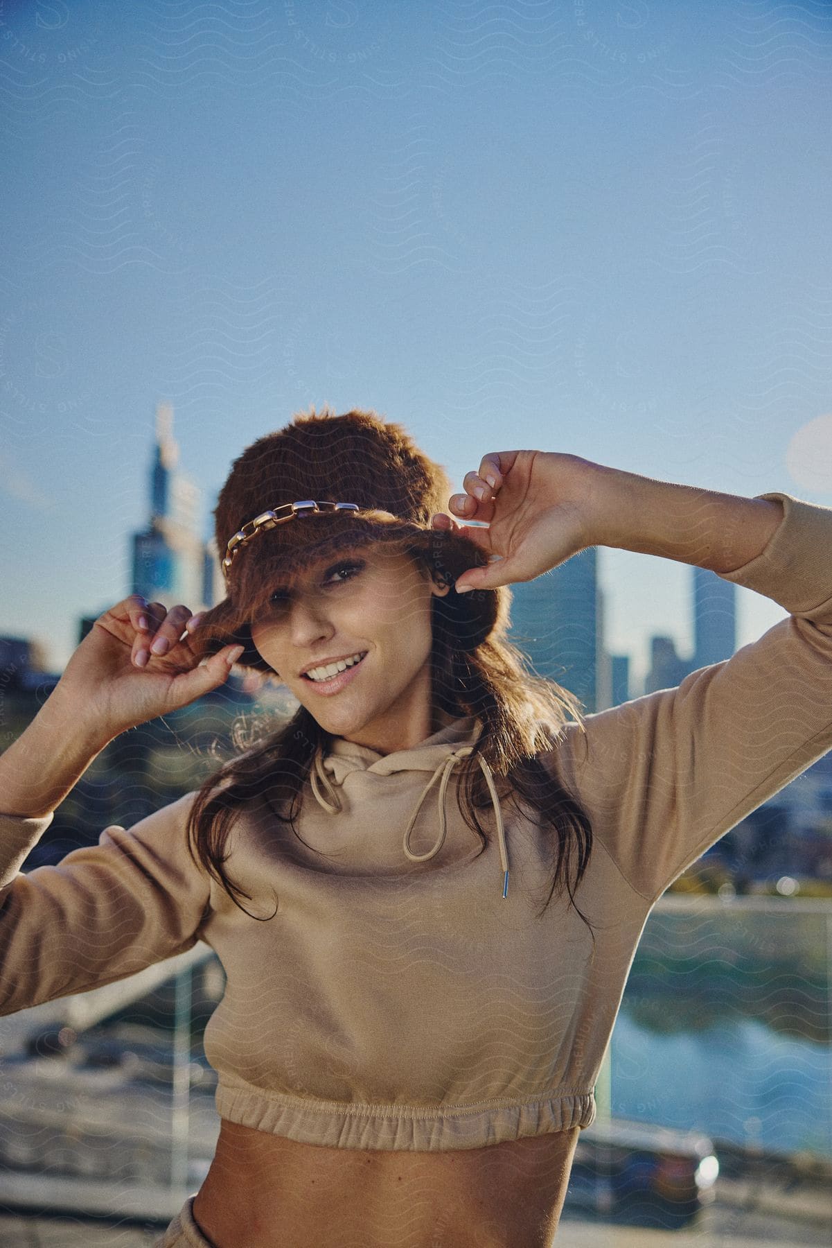 woman models brown fur hat in front of city skyline