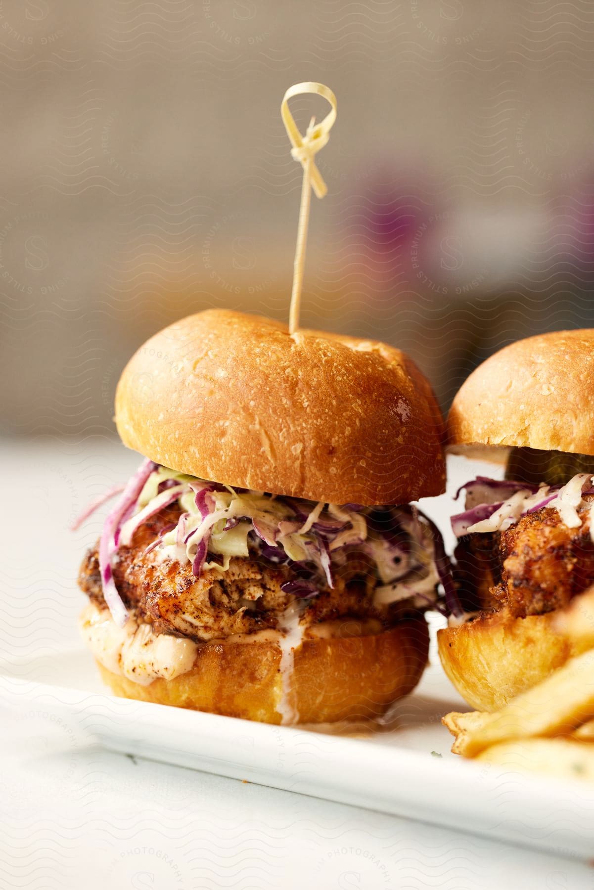 Close-up of two slider sandwiches topped with fresh coleslaw.