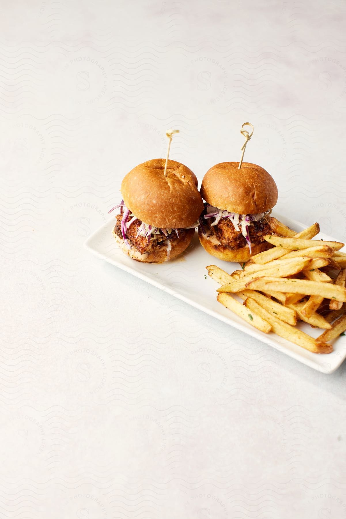 Burgers and fries served on a porcelain plate.