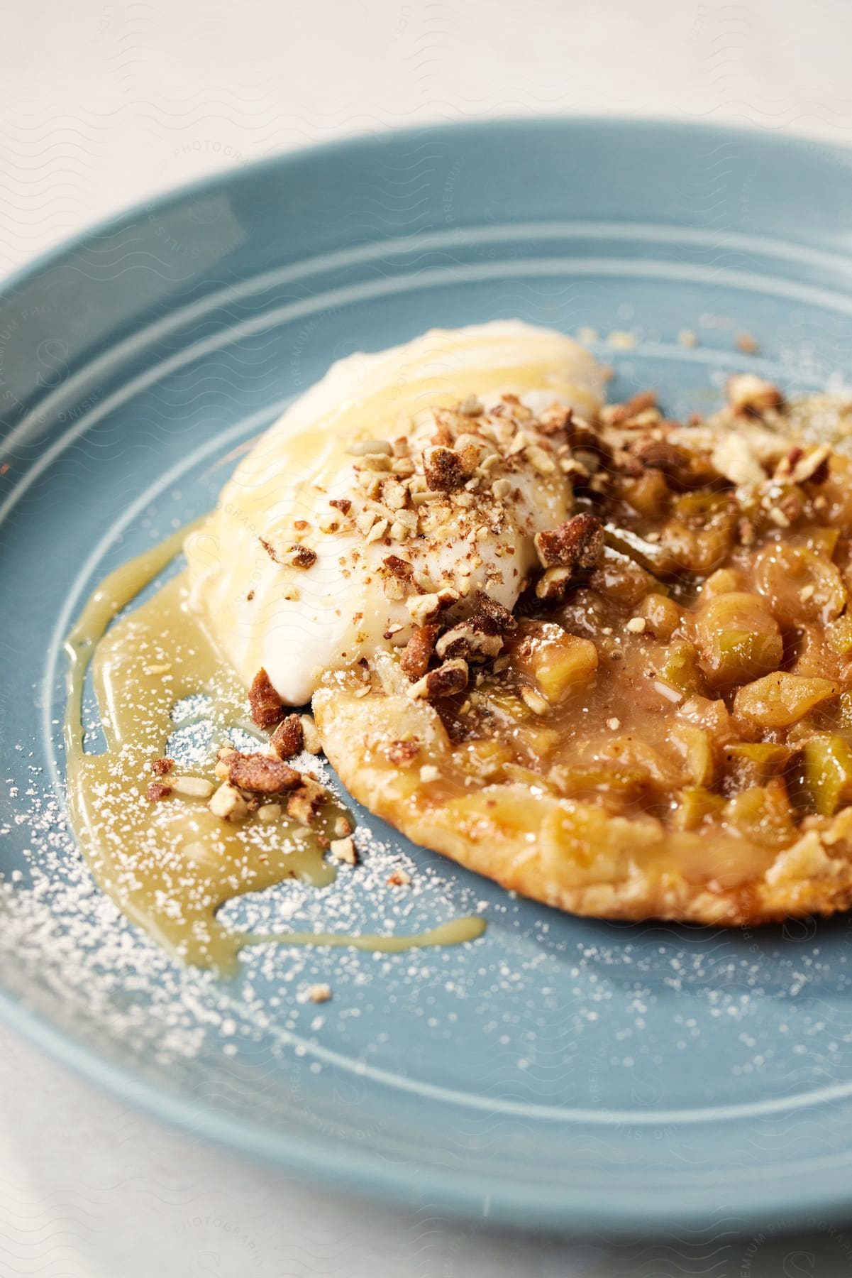 Powdered sugar and nuts top fruit pastry set on a blue plate.