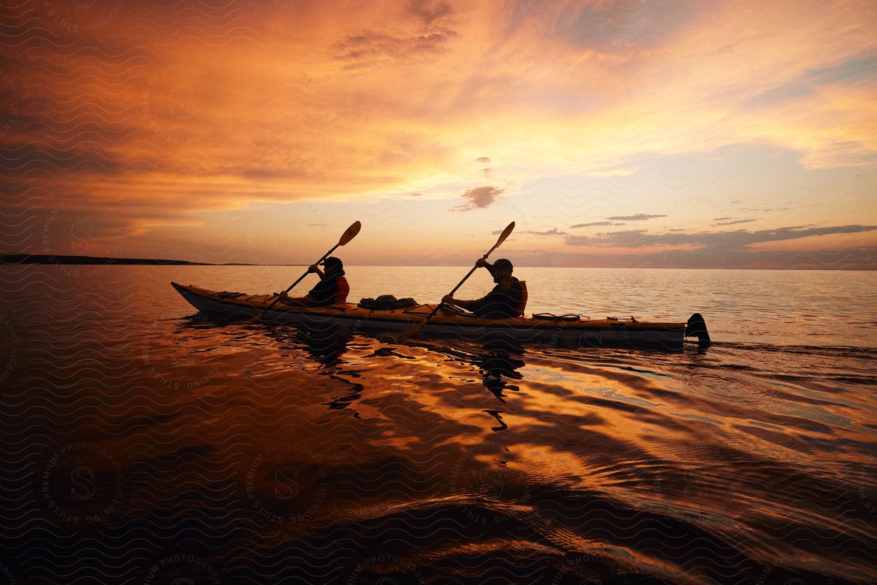 Two men are rowing a canoe as the sun sets on the horizon