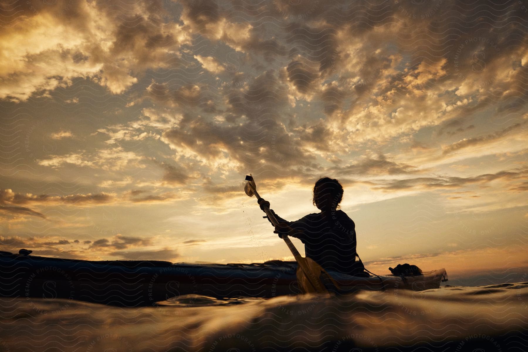 person silhouette paddles canoe at dusk