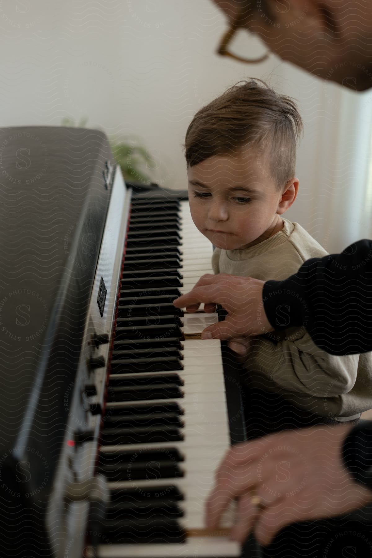 A father teaches his young son how to play an electronic keyboard.