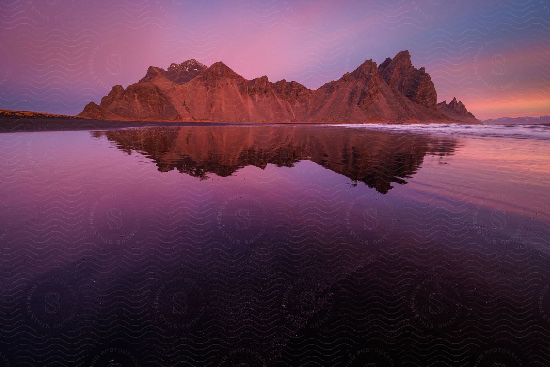 Mountains reflect on the water under a colorful sunset sky