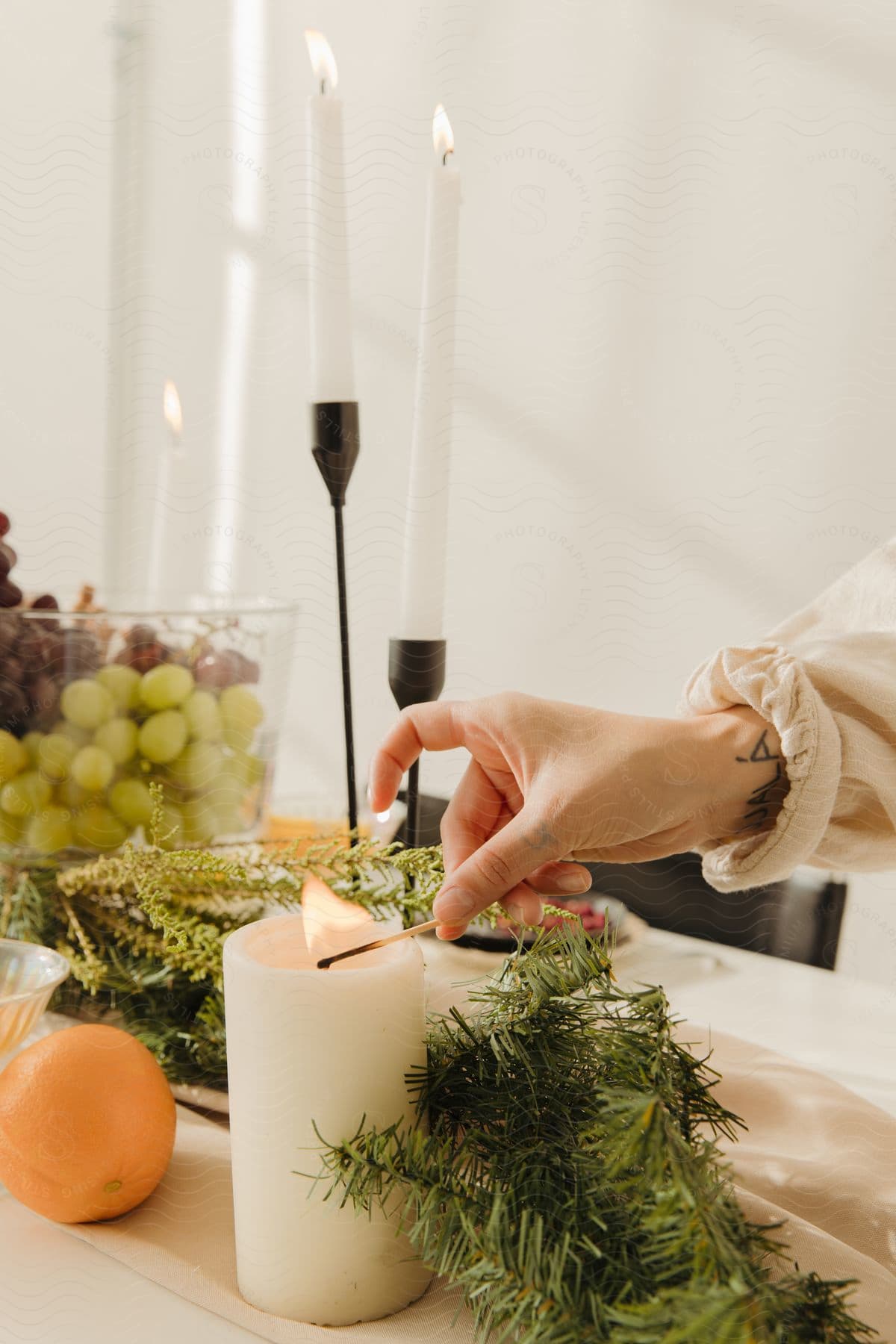 Close up of a person lighting a candle with a match in a room.