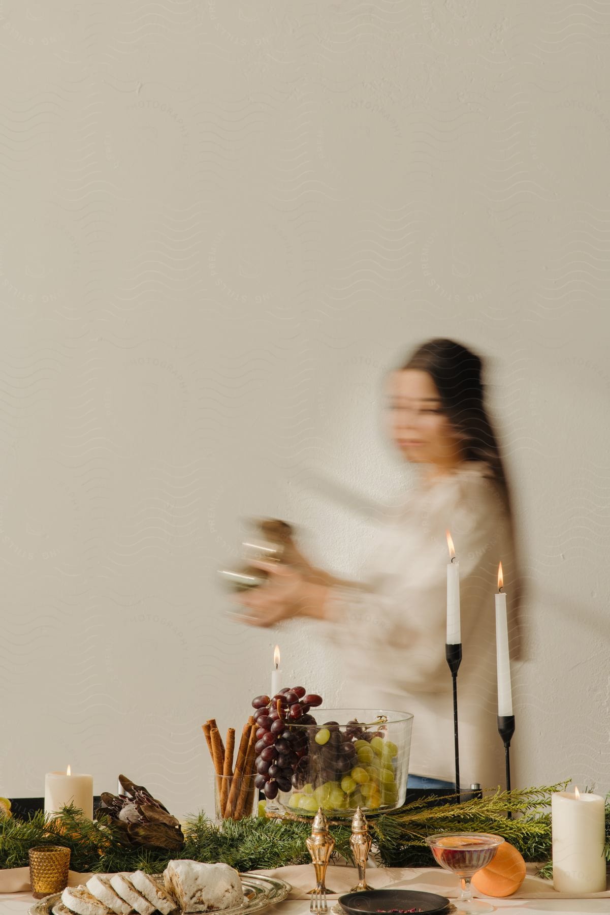 Blurry motion of a woman carrying a gold dish to a candlelit brunch table.