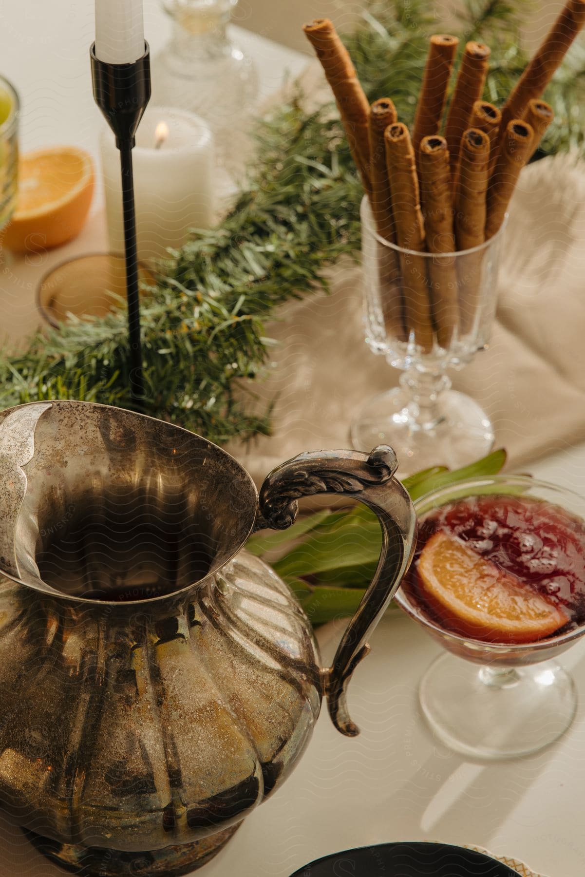 Close-up of a festive table with candles, cinnamon, and a pitcher.