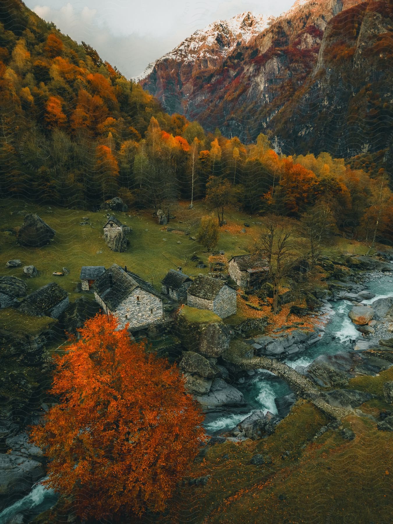 Houses along a stream in a small mountain valley village with trees in bright fall colors