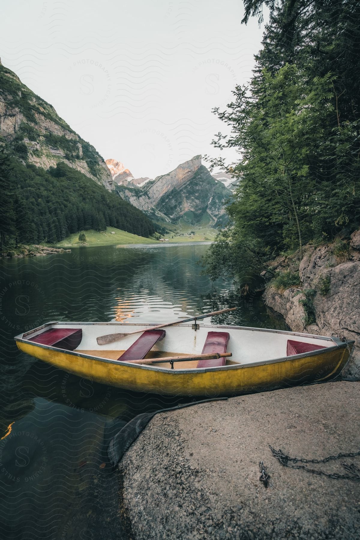 Canoe resting on a calm lakeshore with mountain backdrop.