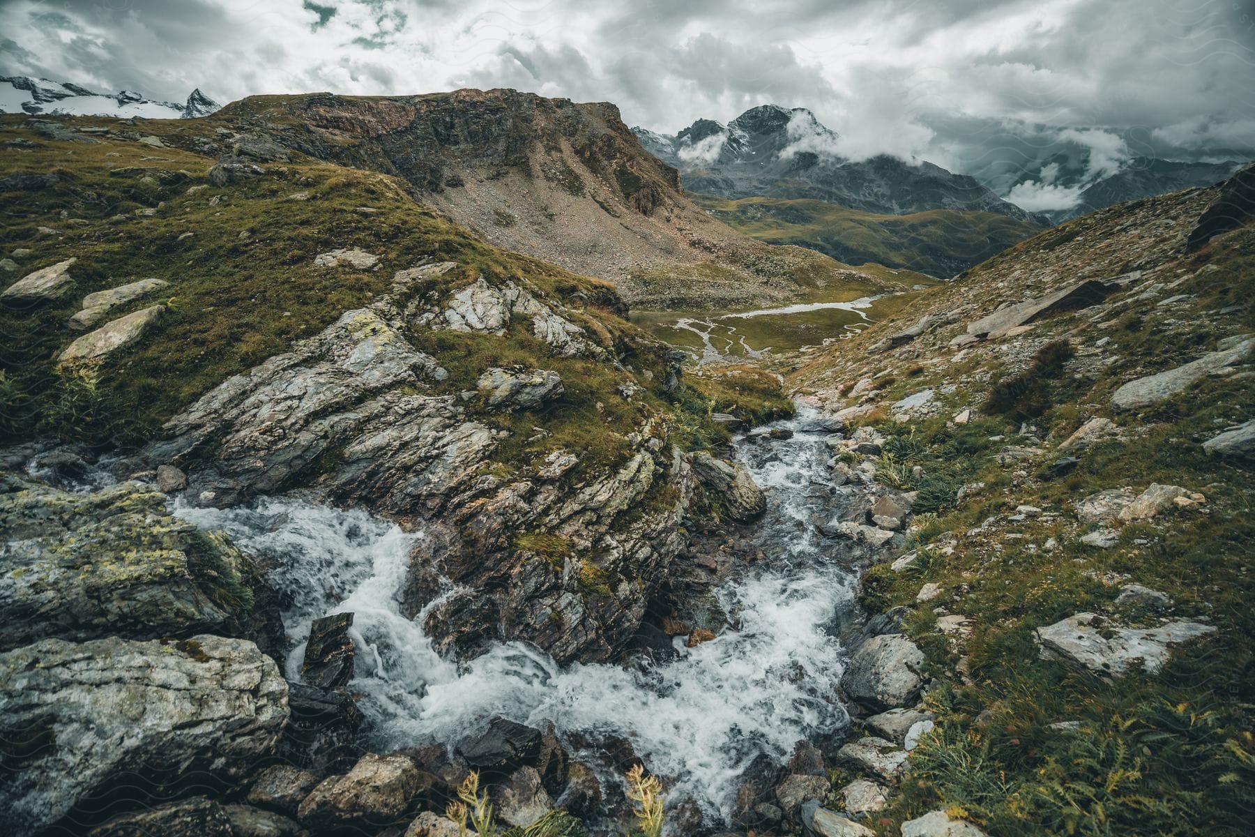 A stream between valley and mountains during the day.