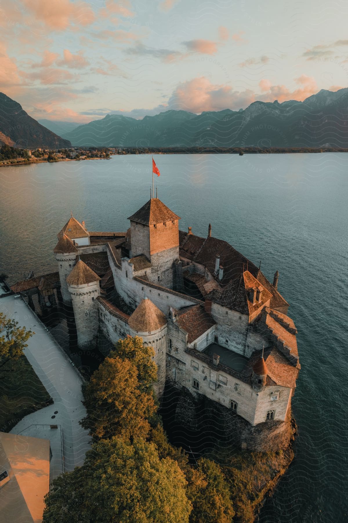 A lone red flag crowns a castle island, nestled amidst a mountain-guarded lake.