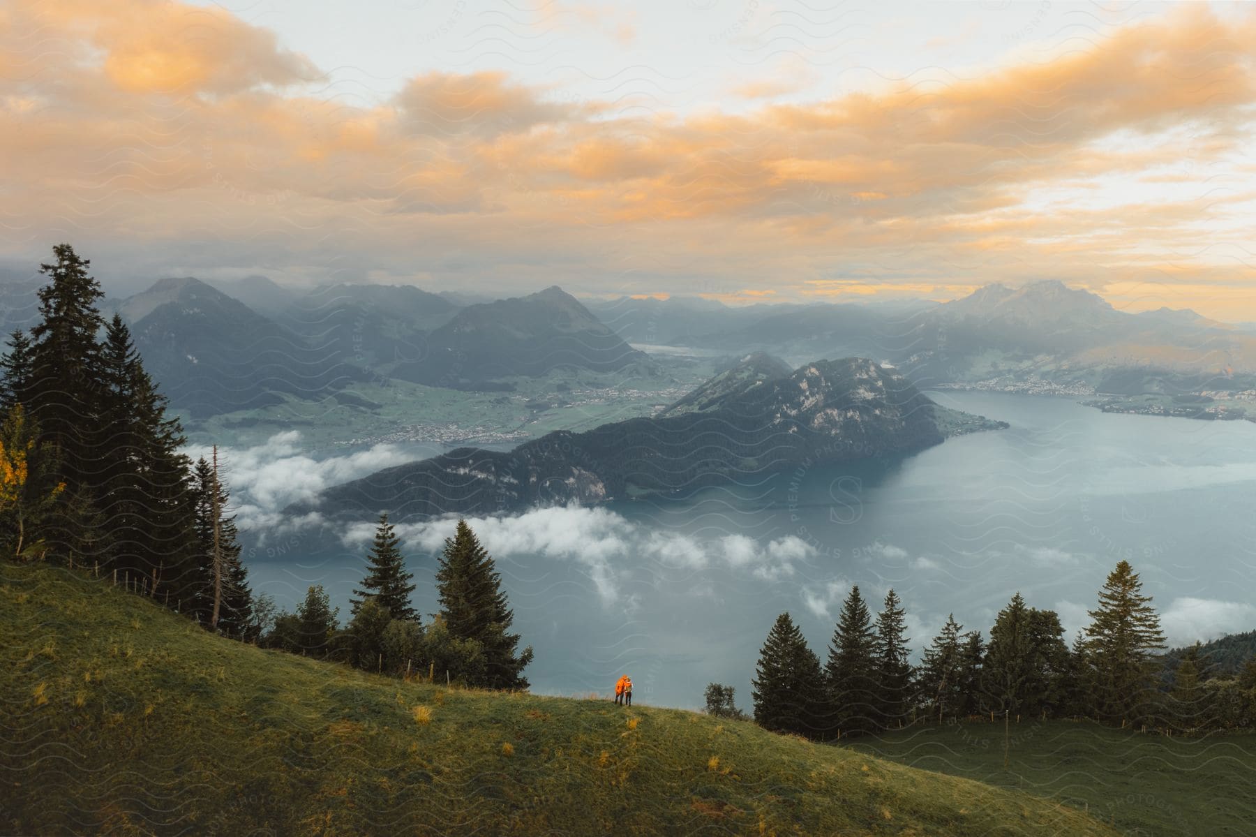 View of a landscape with the sea, a mountain range, and an orange morning sky.