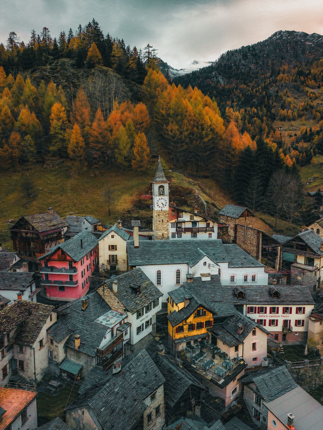 A quaint village nestles beneath a mountain ablaze with autumn colors, its lone clock tower keeping time over a patchwork of homes.