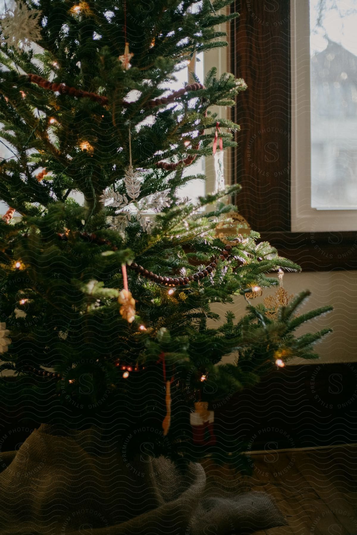 A decorated Christmas tree set near a window on a gray day