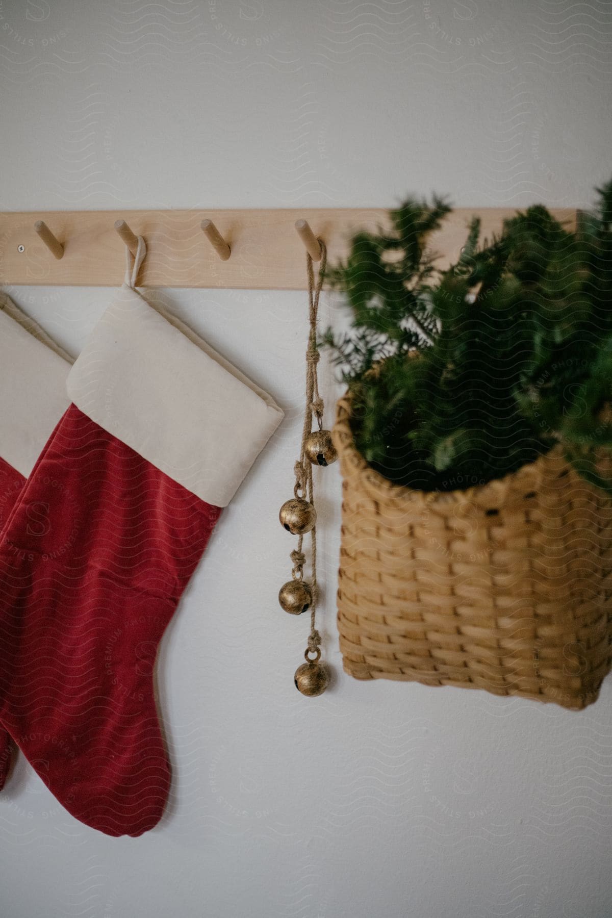 Christmas stockings, jingle bells, and a basket hang off a wall mounted peg rack.