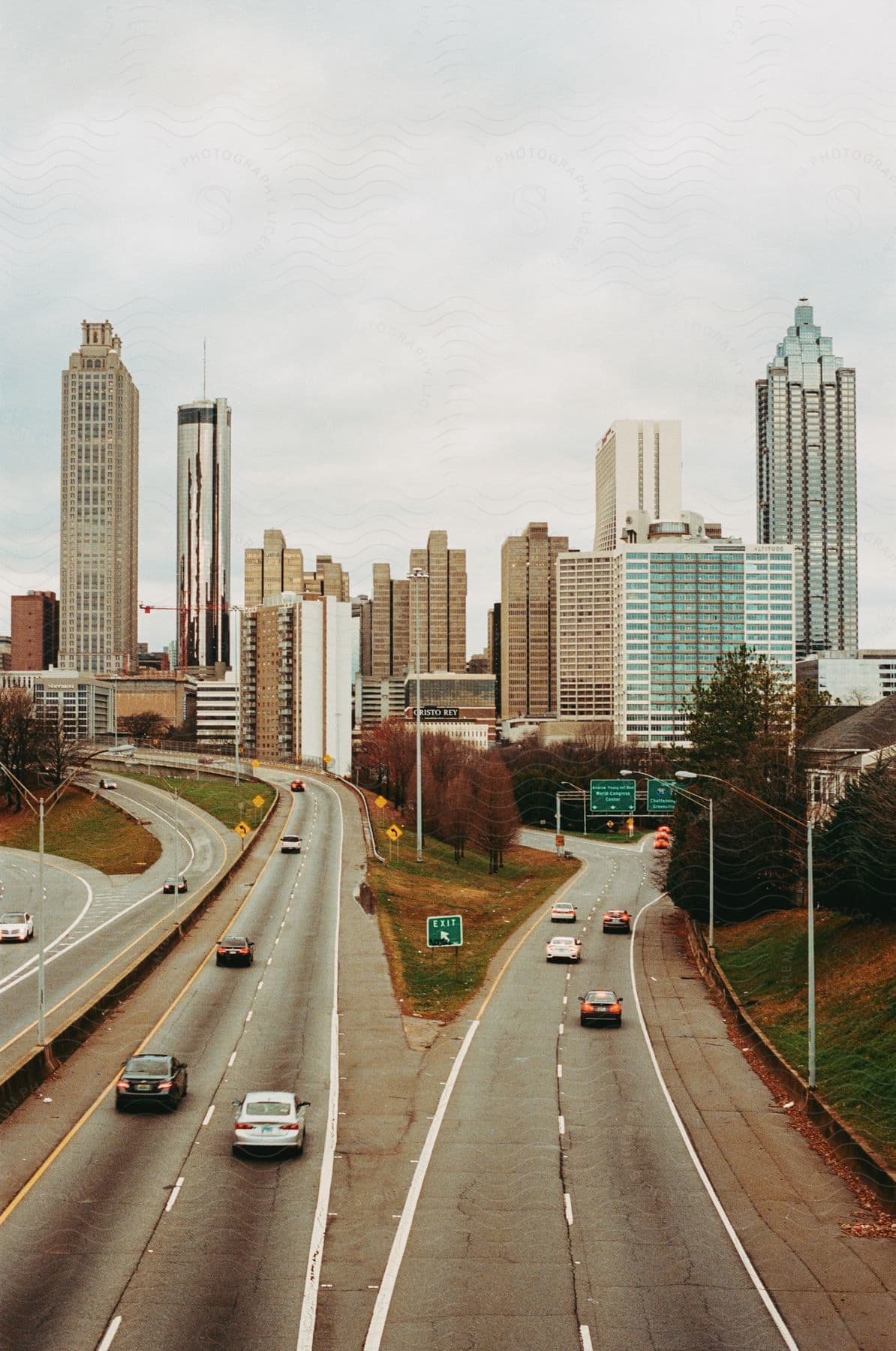 Some tall buildings in a city with a highway leading into the town.