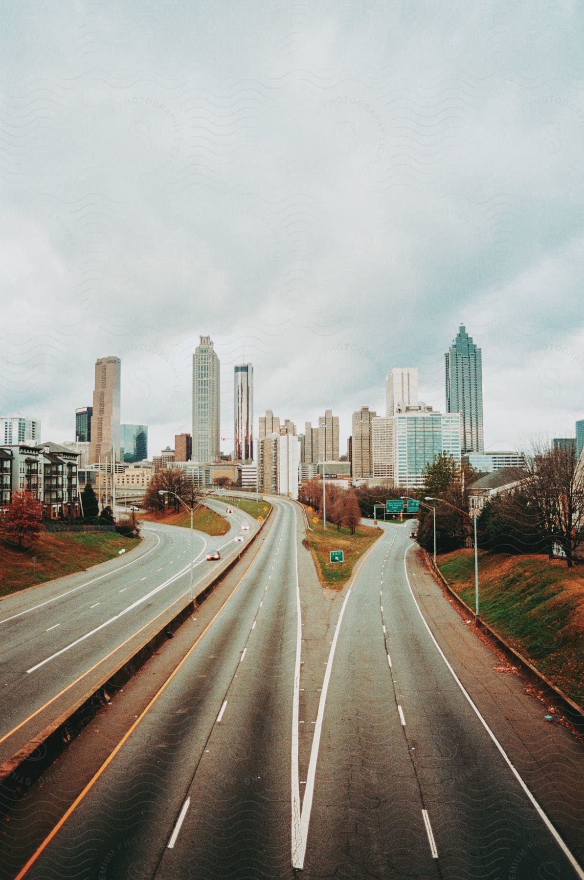 Rainy highway streams into a city of steel giants under a leaden sky.