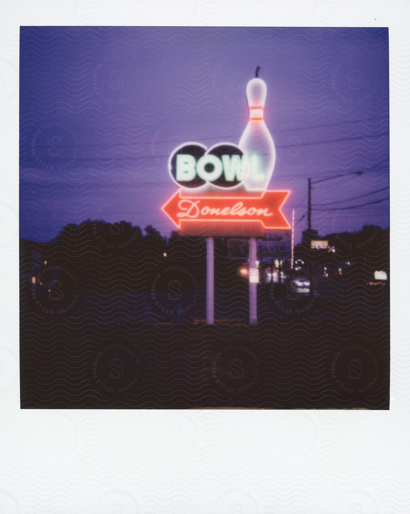 A vintage bowling alley sign illuminated by a neon glow at night, captured in a polaroid photograph.