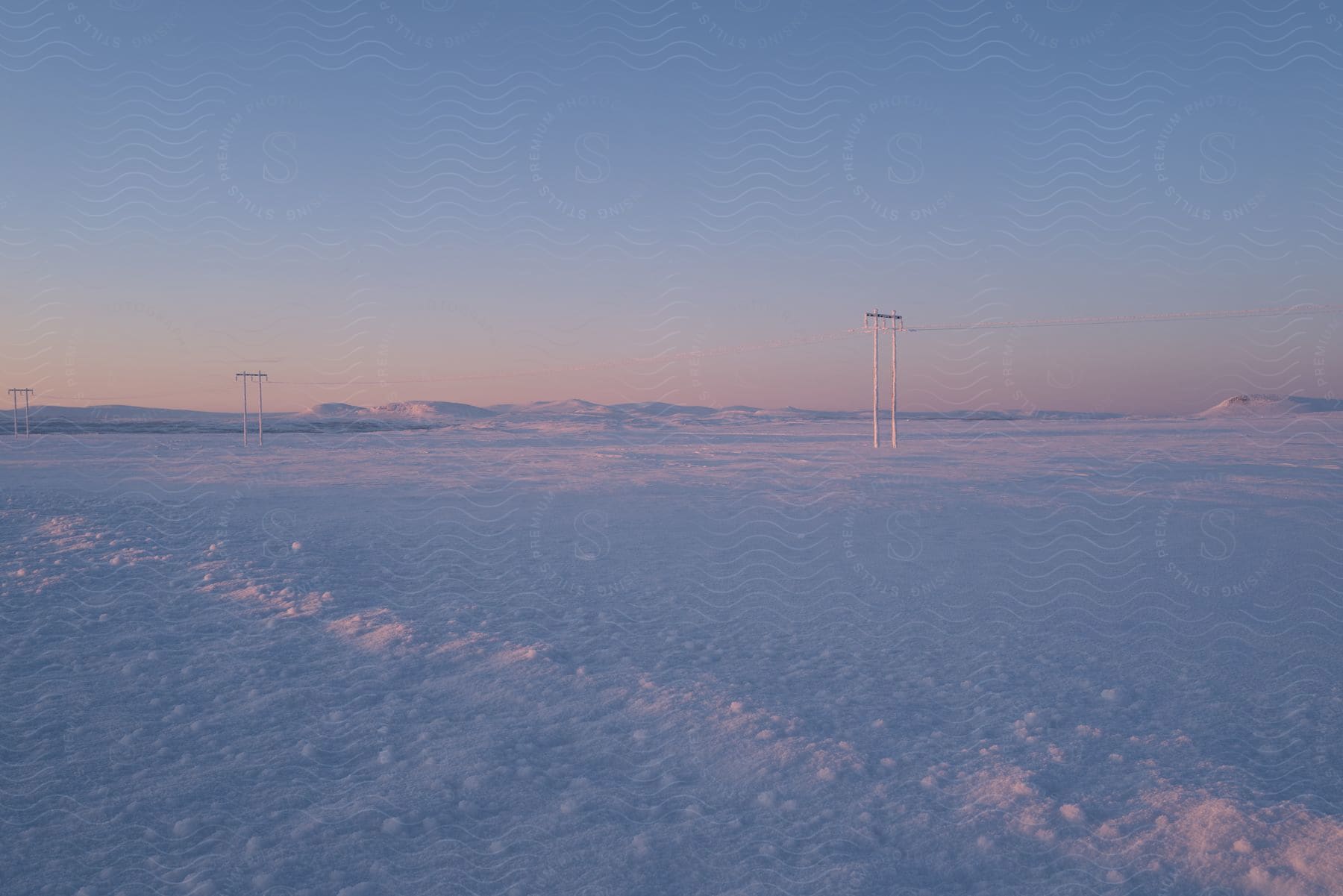 Power lines crossing a snow-covered plain.