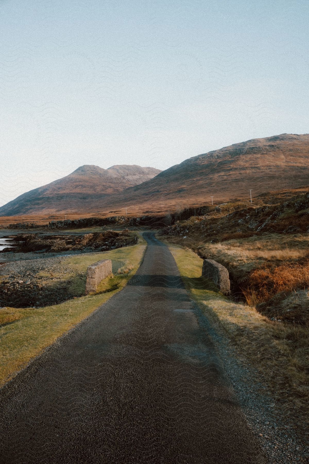 A small asphalt road in a region with some hills with rocks on top