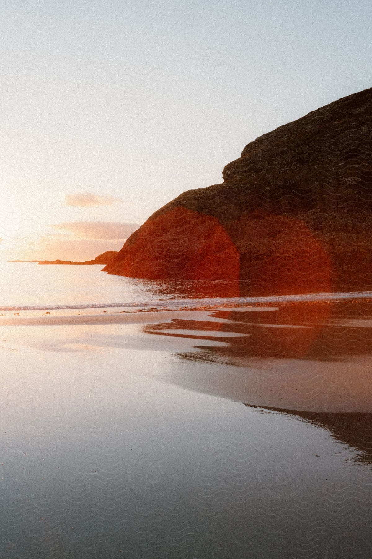 Red reflection on a hillside next to the beach at sunset.