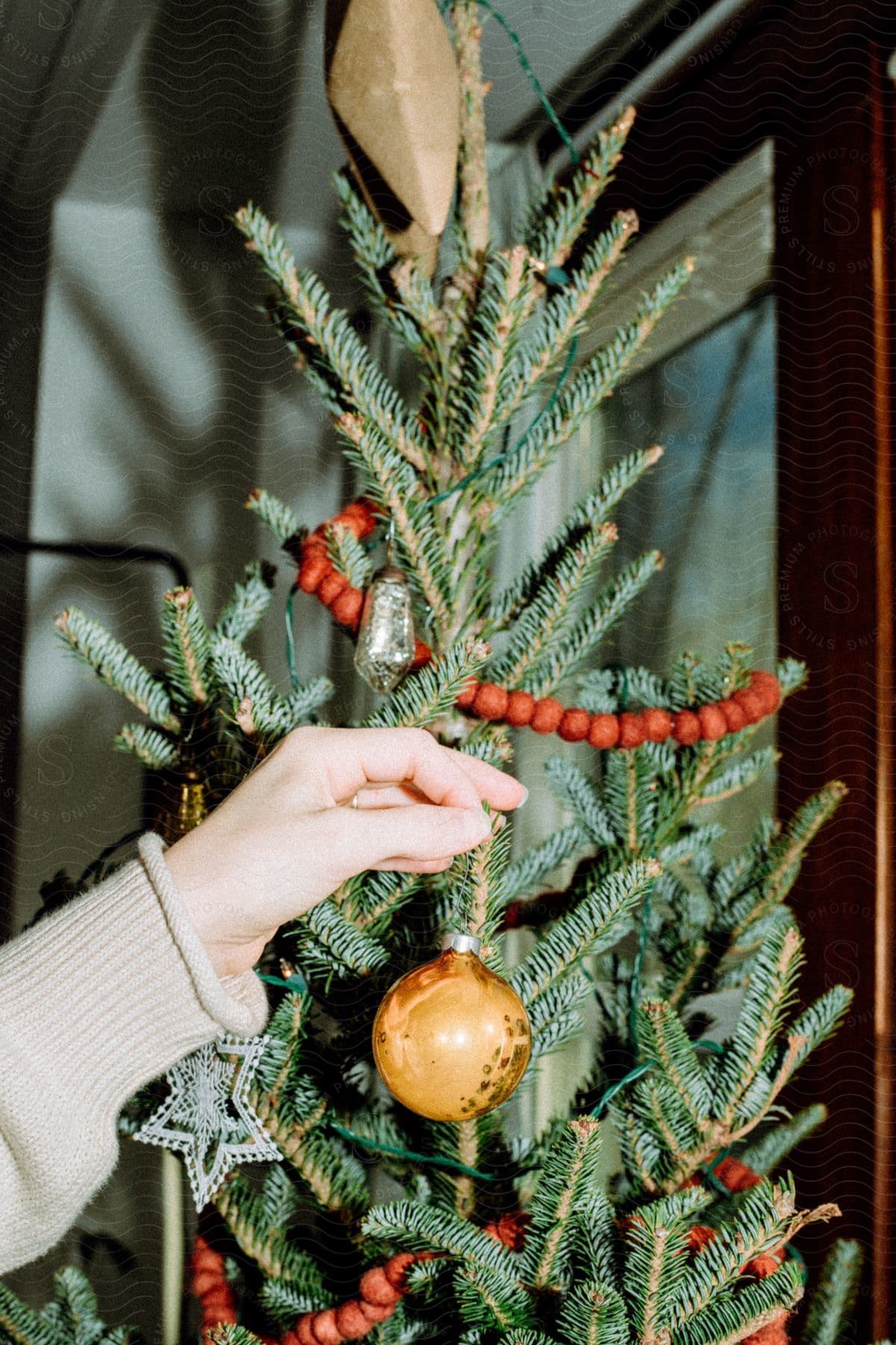 Woman hangs ornament on a Christmas tree.