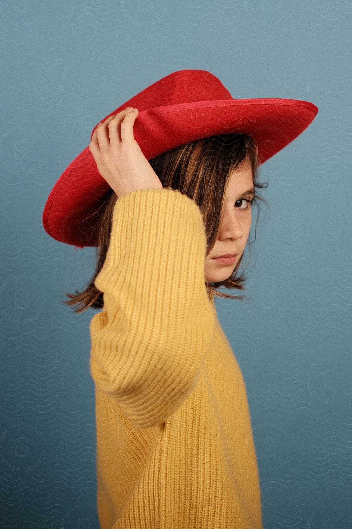 A child in a red hat posing on a blue background