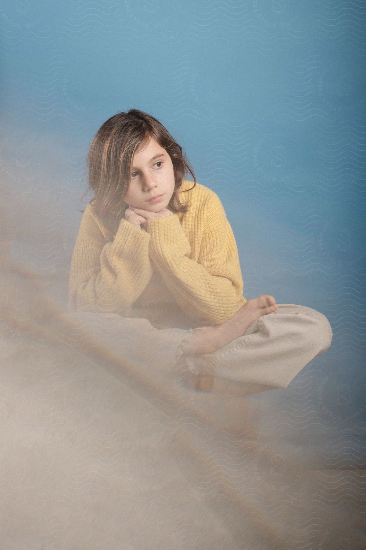 A boy wearing a knitted sweater is sitting in a lotus yoga pose.