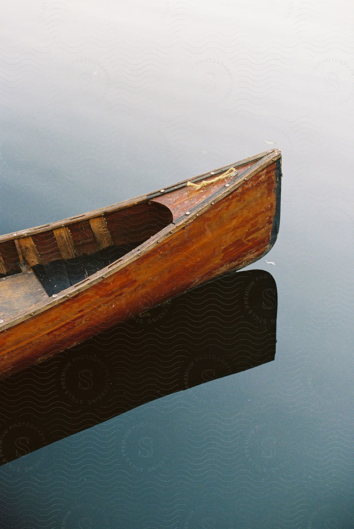 A wooden canoe sits on a still body of water.