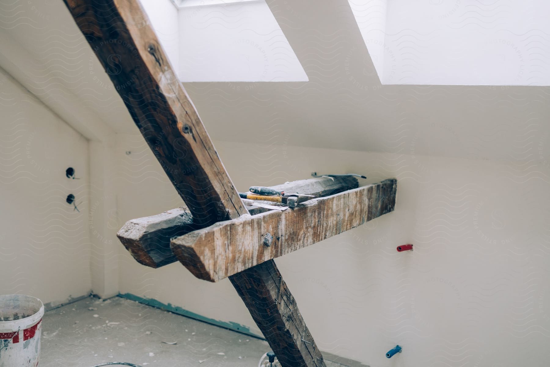 A load-bearing beam is being temporarily supported during a home renovation while a skylight is installed in the ceiling.