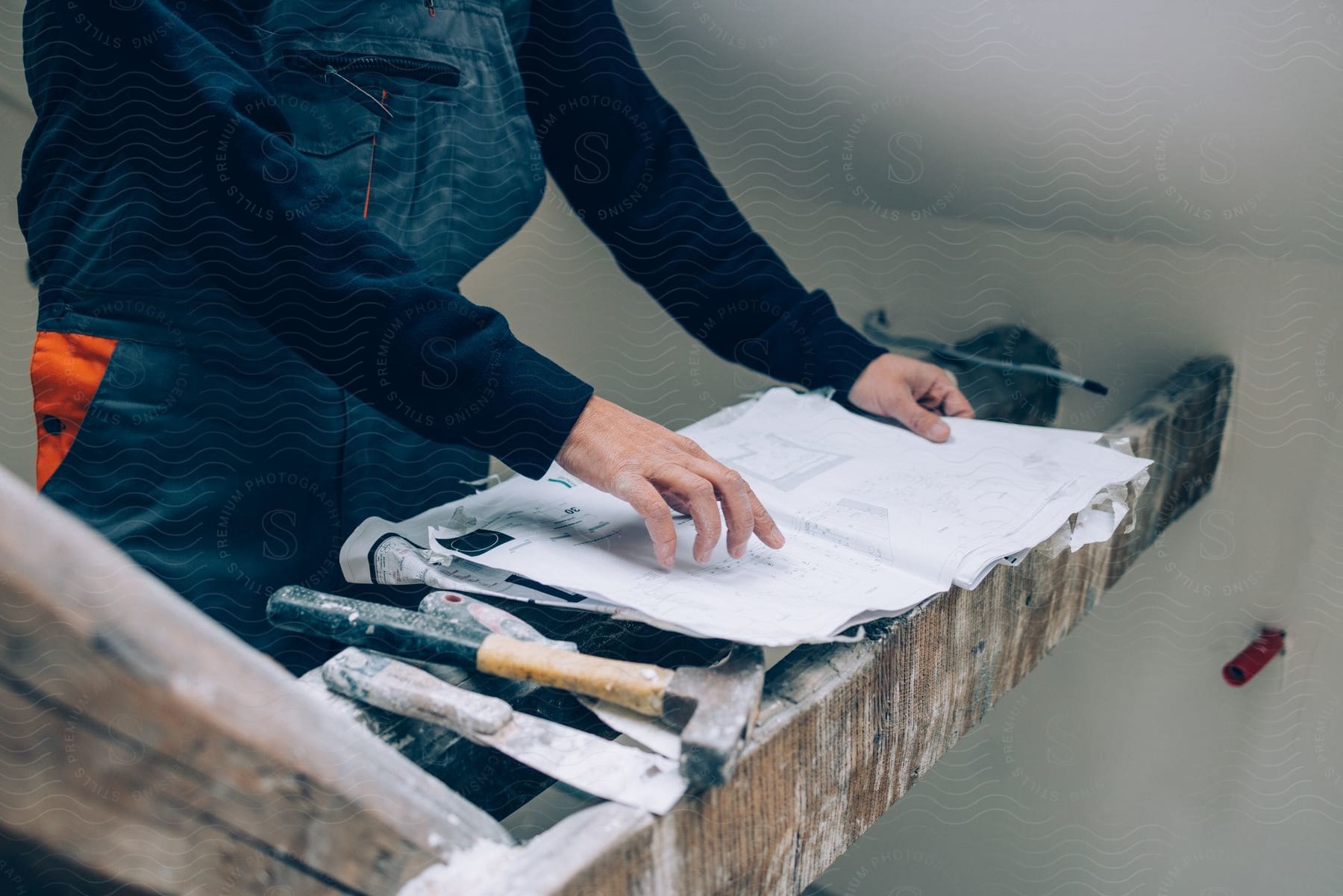 A craftswoman is looking at plans with a hammer and chisel nearby