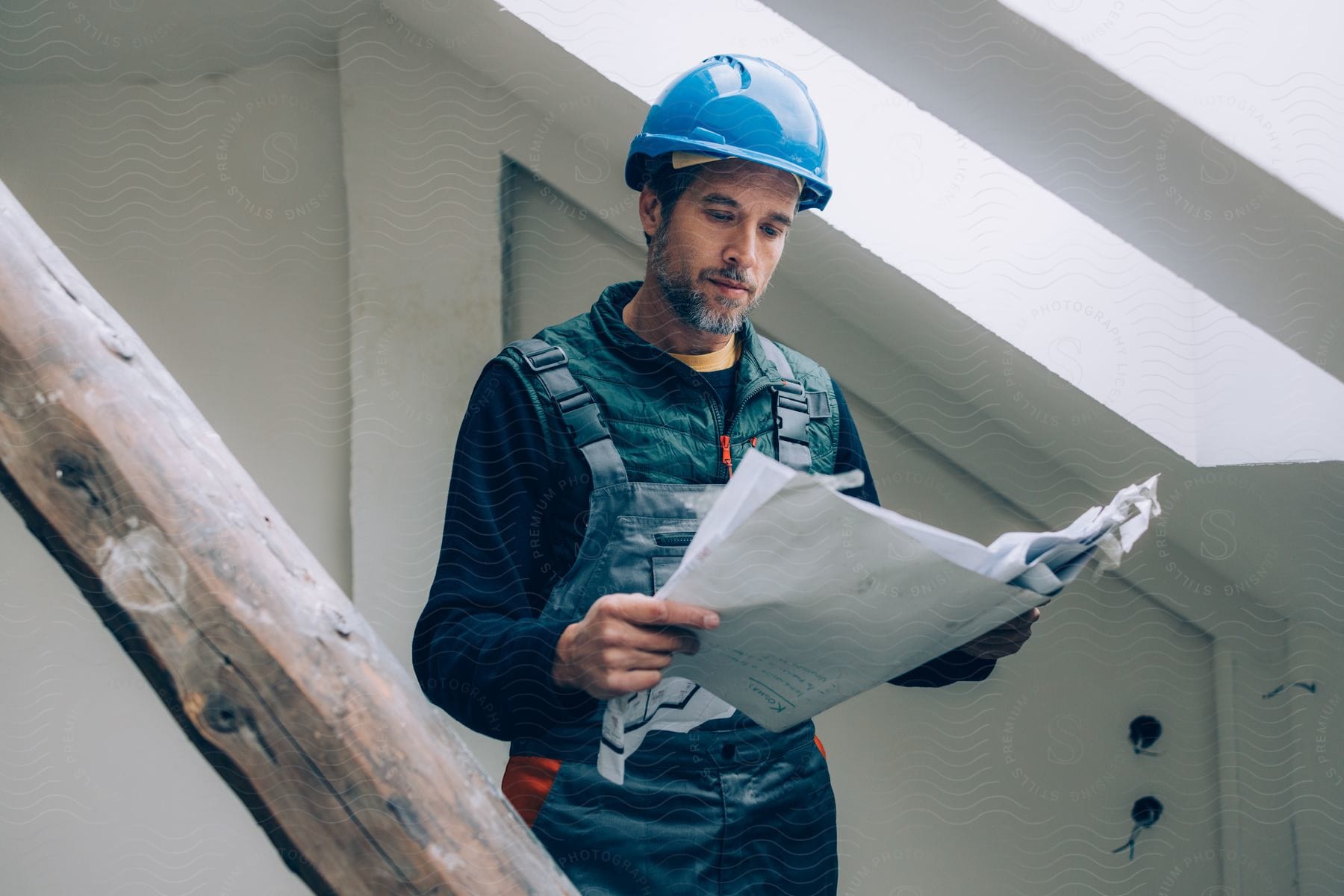 Man in overalls analyzing a project with a protective helmet.