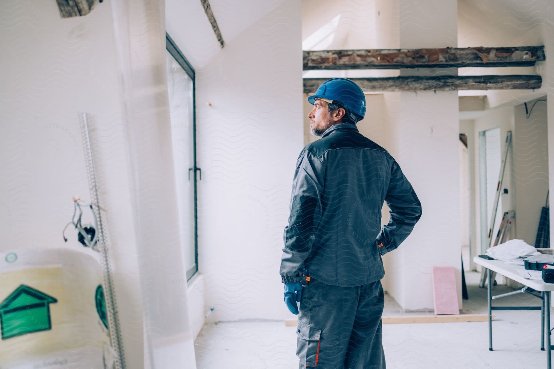 A contractor in standard workwear stands in a home undergoing renovations.