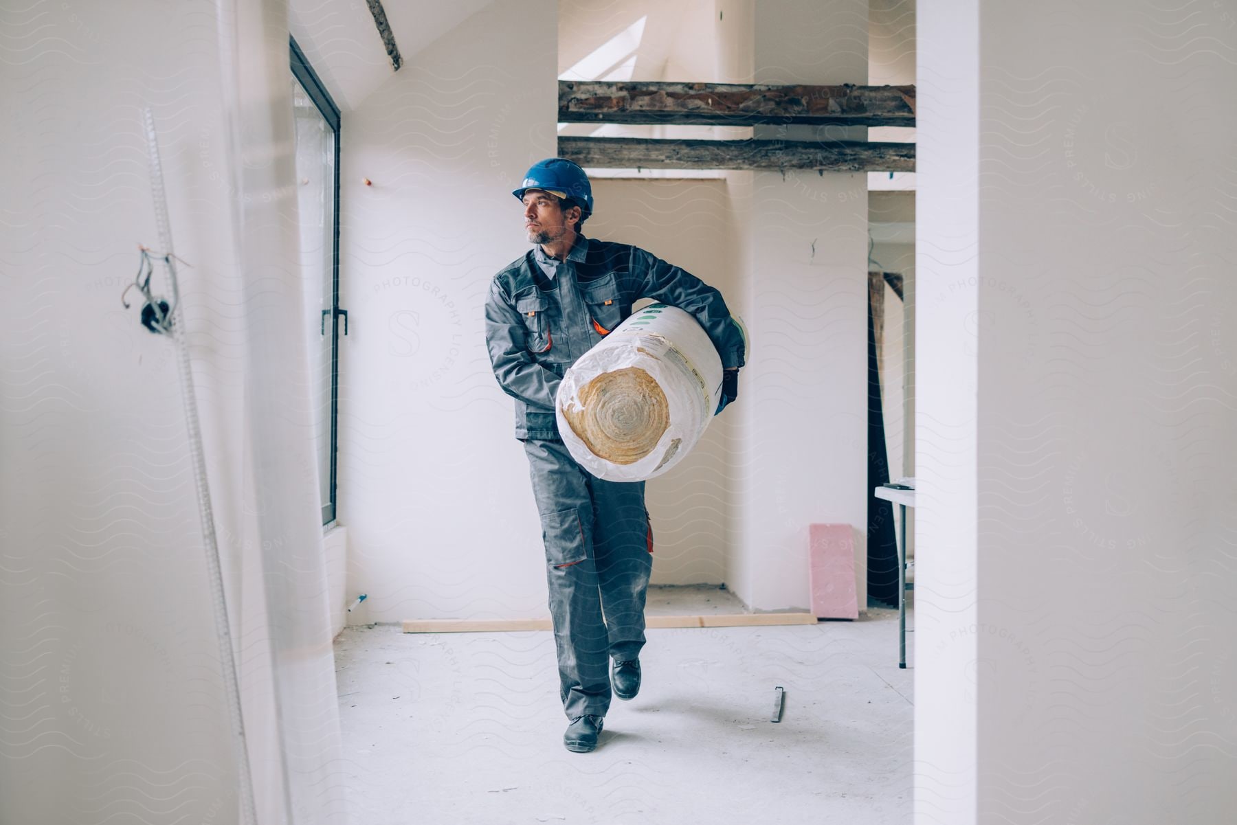 A man carrying construction materials in a building.