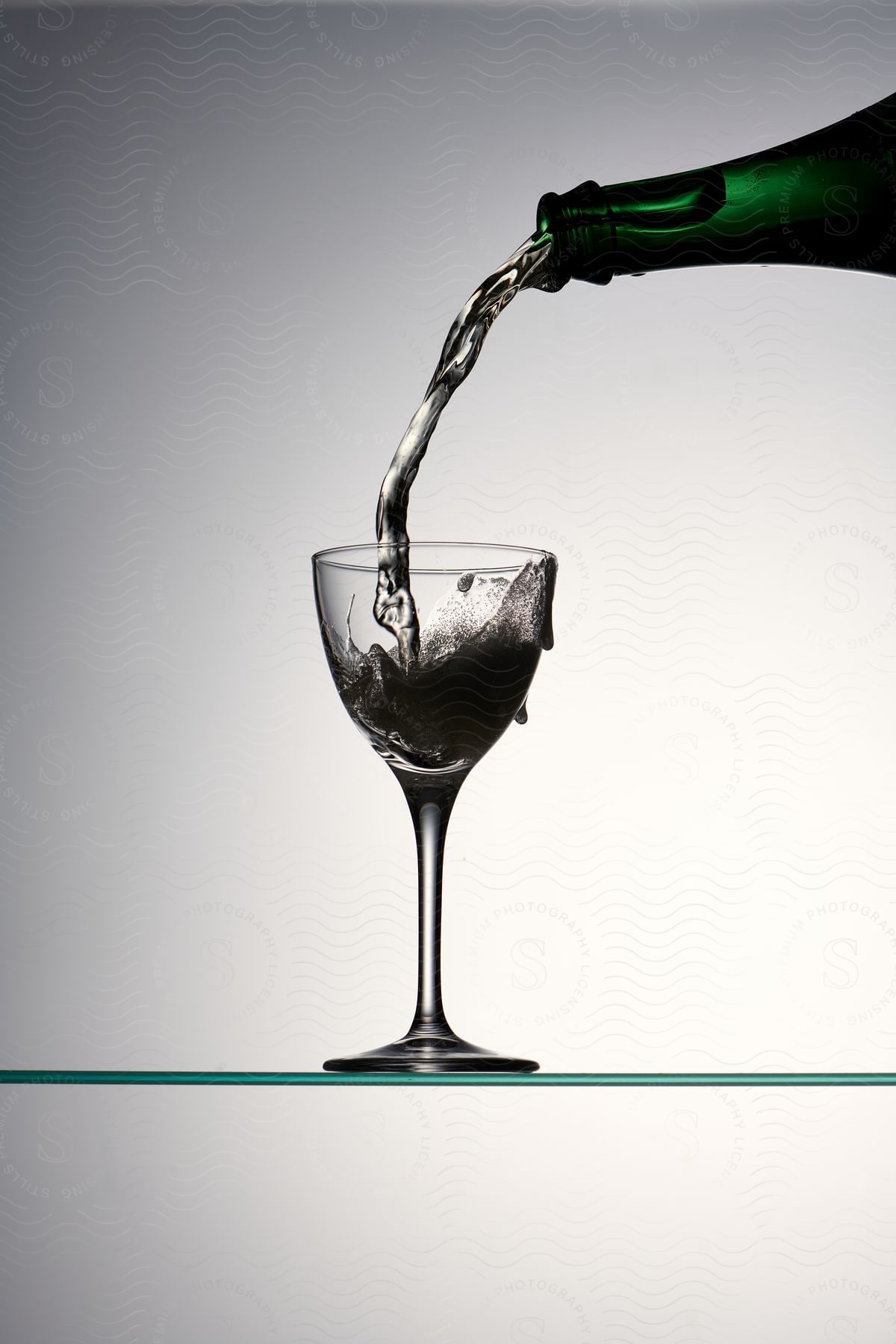 Pouring liquid from a green bottle into a wine glass.