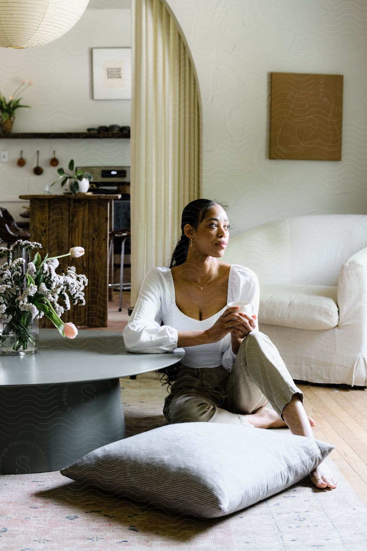 A woman modeling some clothes while sitting on the floor in a house.