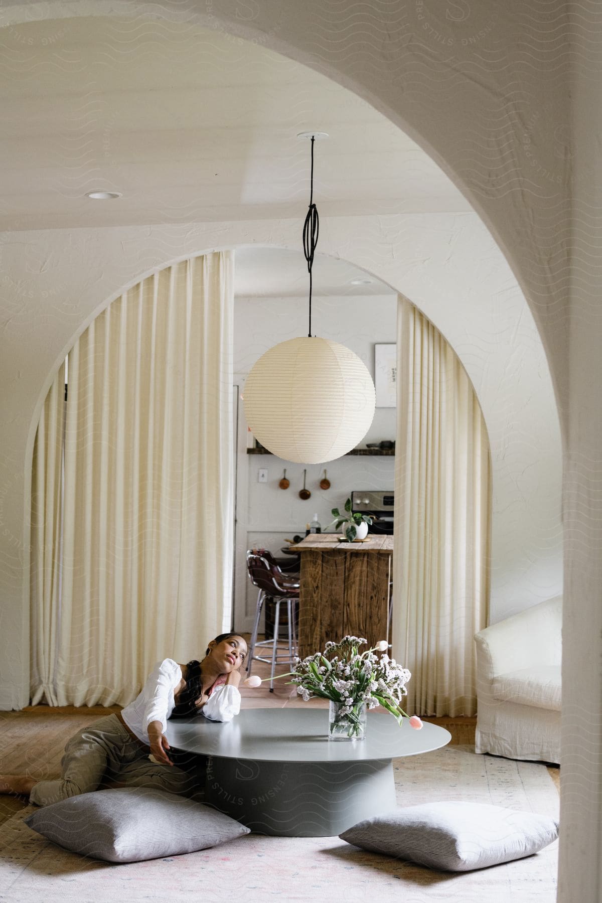 Interior design of a room with a central table where a woman is leaning and sitting on the floor.