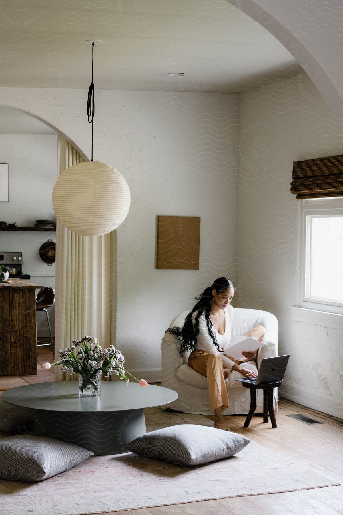 A woman sitting in an armchair and working on a laptop in front of her