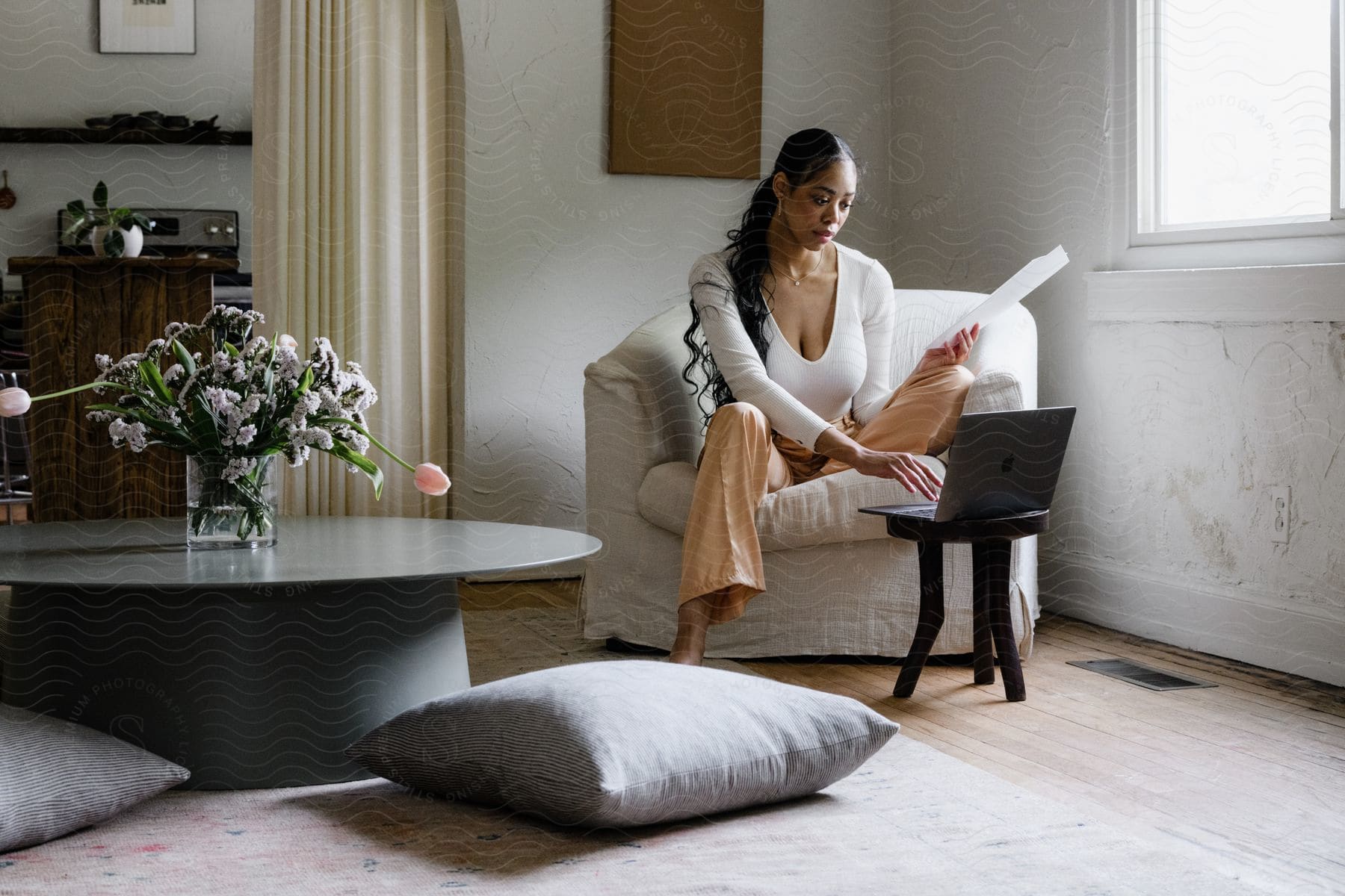 A concentrated woman working on a laptop in the living room.