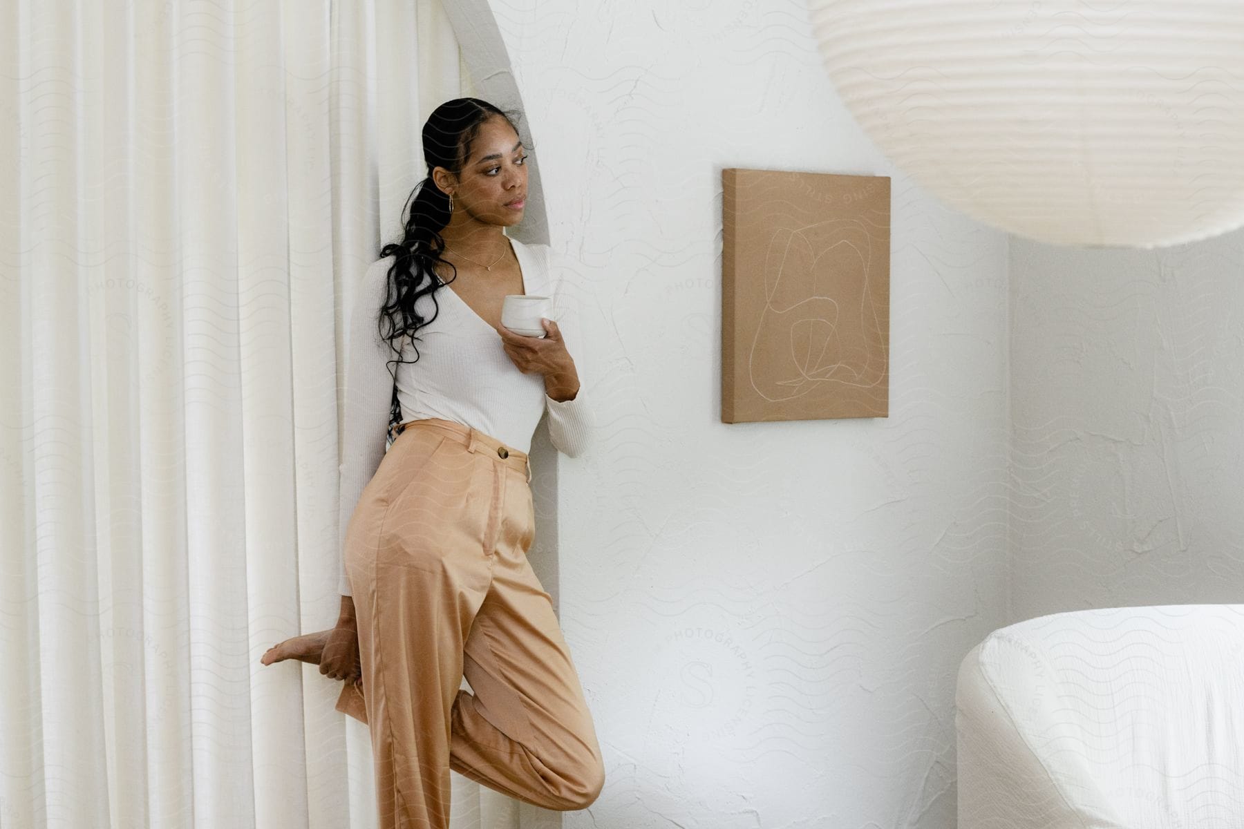 Woman with a glass in hand posing in a white interior design environment.