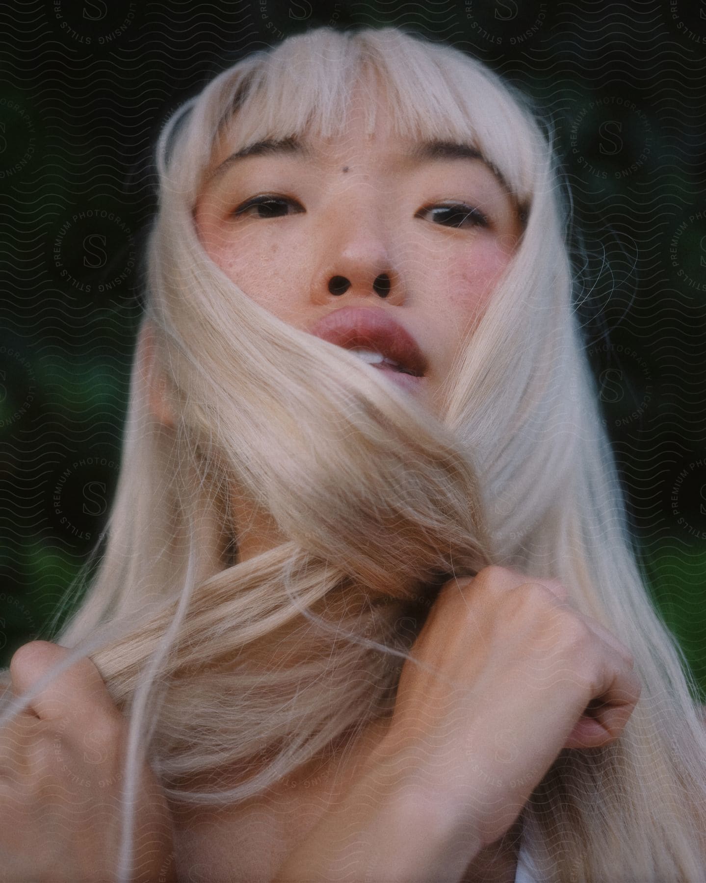 blonde woman crosses hair under chain and poses