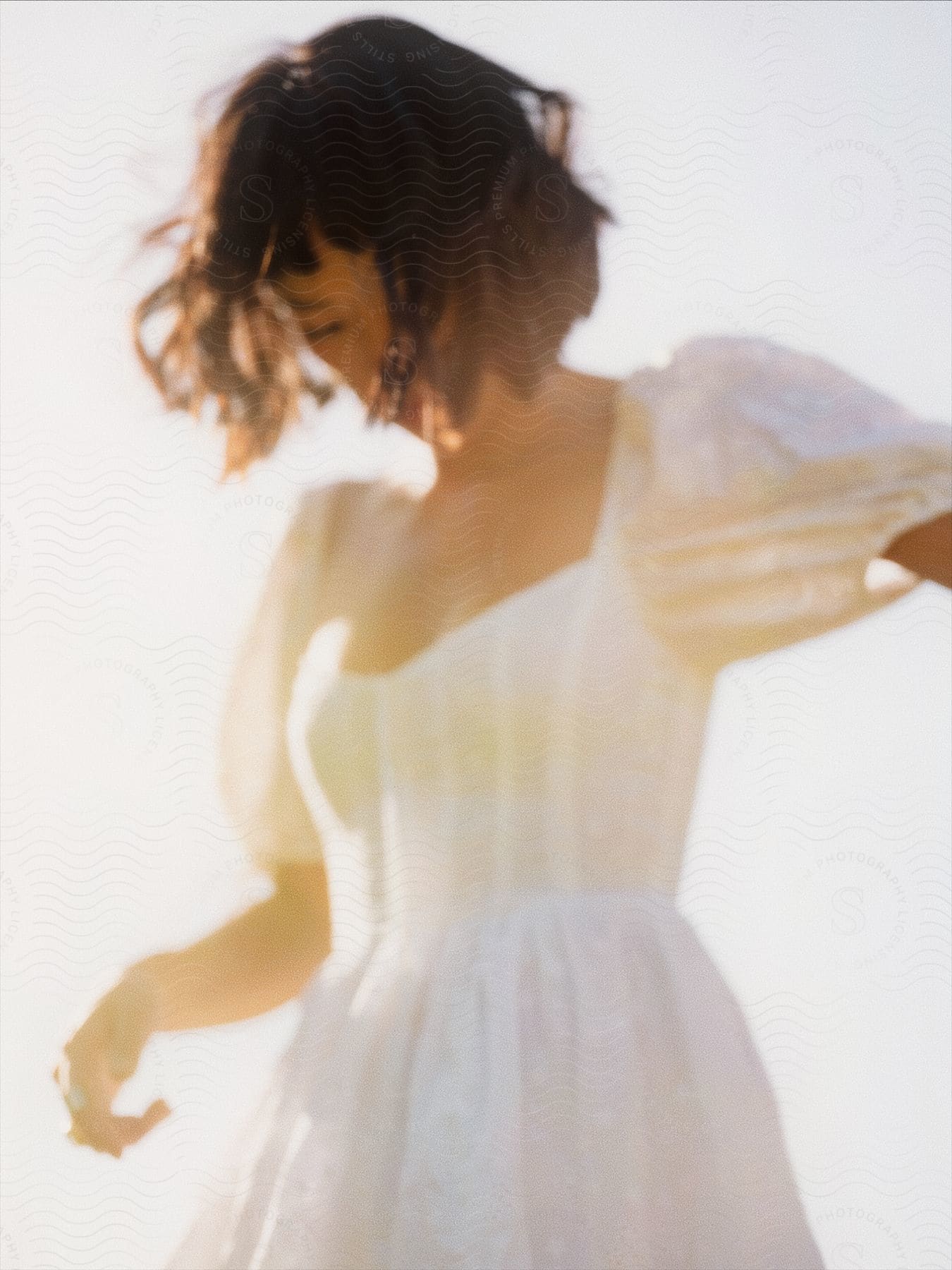 A young woman wearing a white dress is looking down