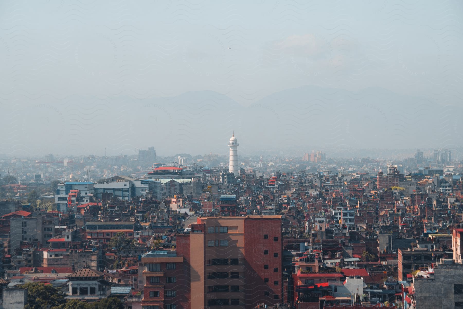 An aerial view of a large densely populated city area with a tower at the center.