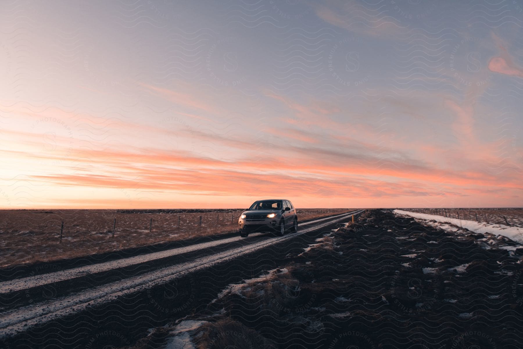 An suv driving on a deserted highway through the plains at sunset