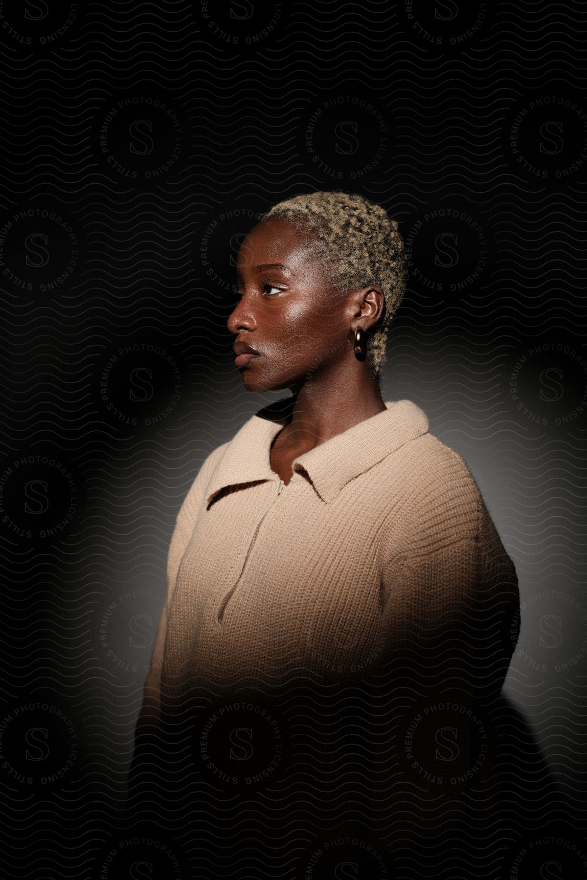 An African woman with blonde hair and wearing earrings is posing for the camera