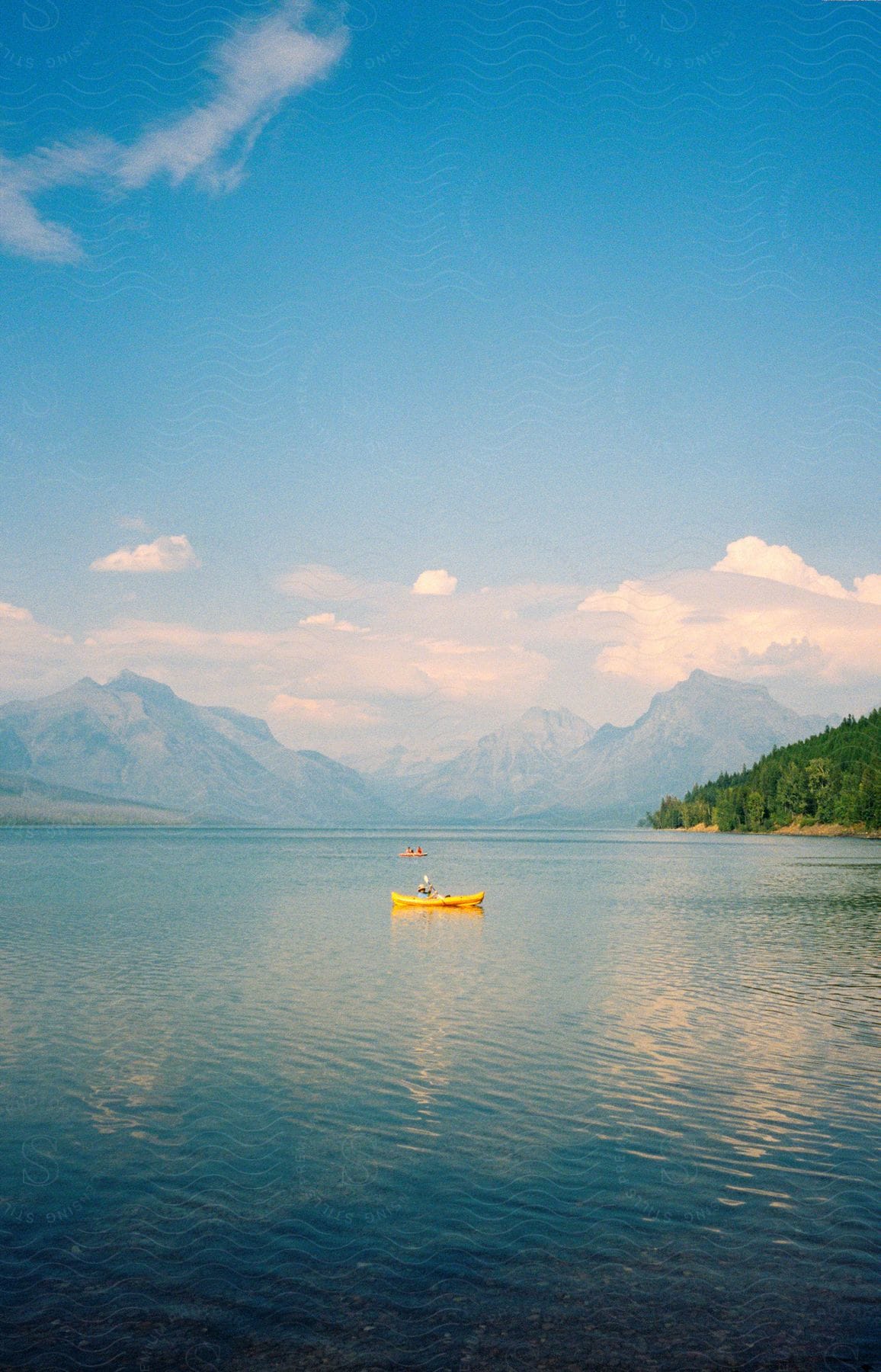 two canoes on a lake by a large mountain range.