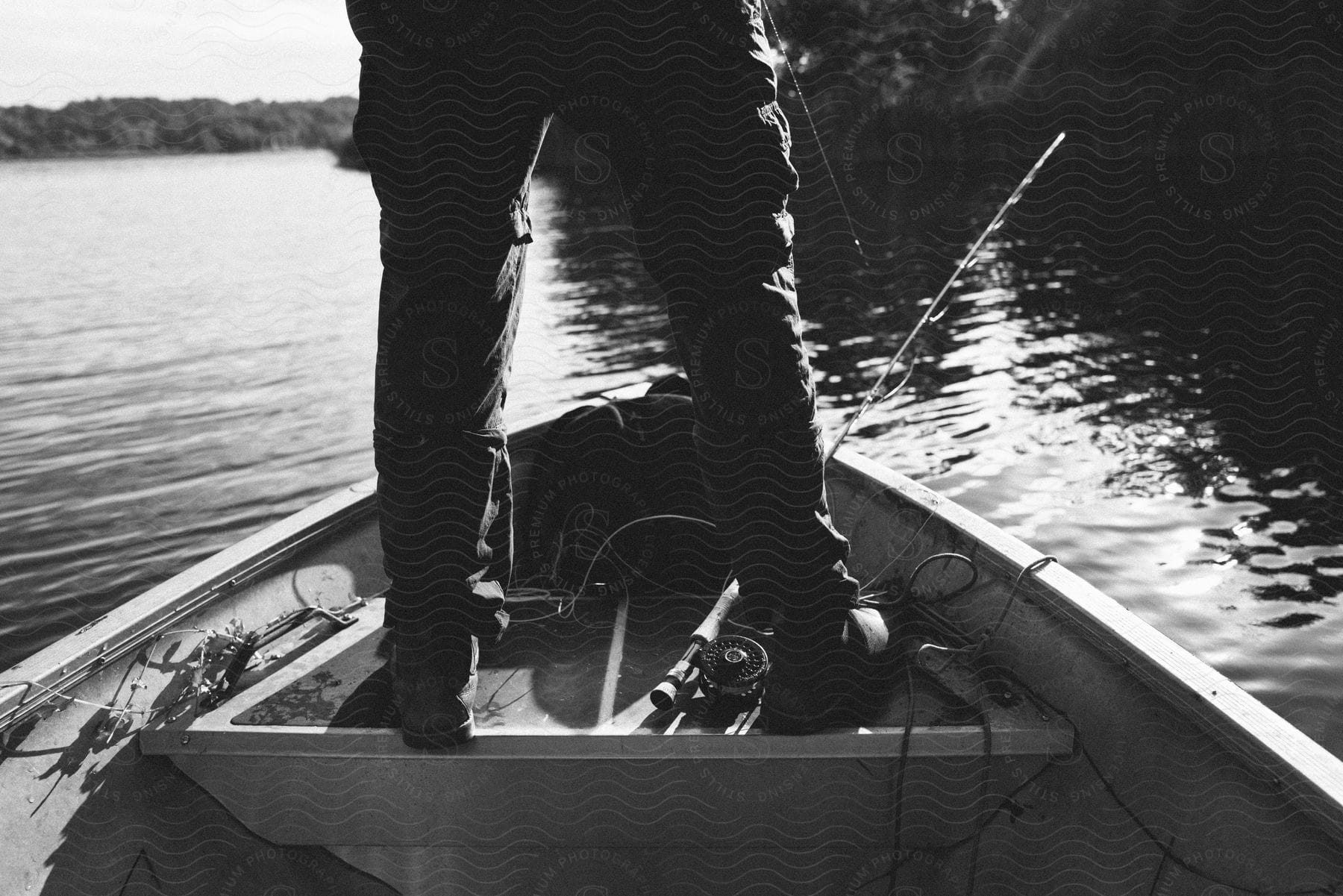Fisherman standing in his small boat as his pole leans against the side over the water